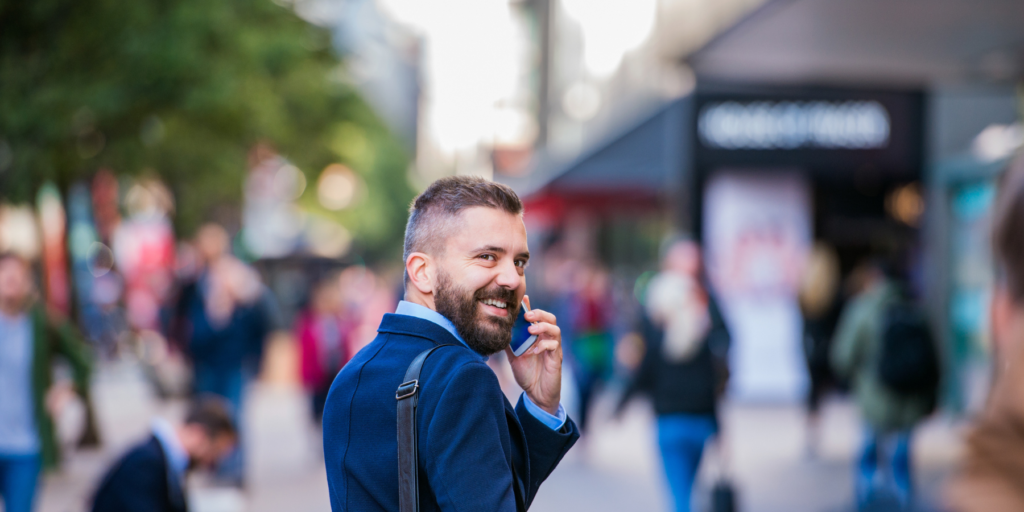 hombre adulto vestido formal camina por la calle y habla por teléfono en actitud sonriente