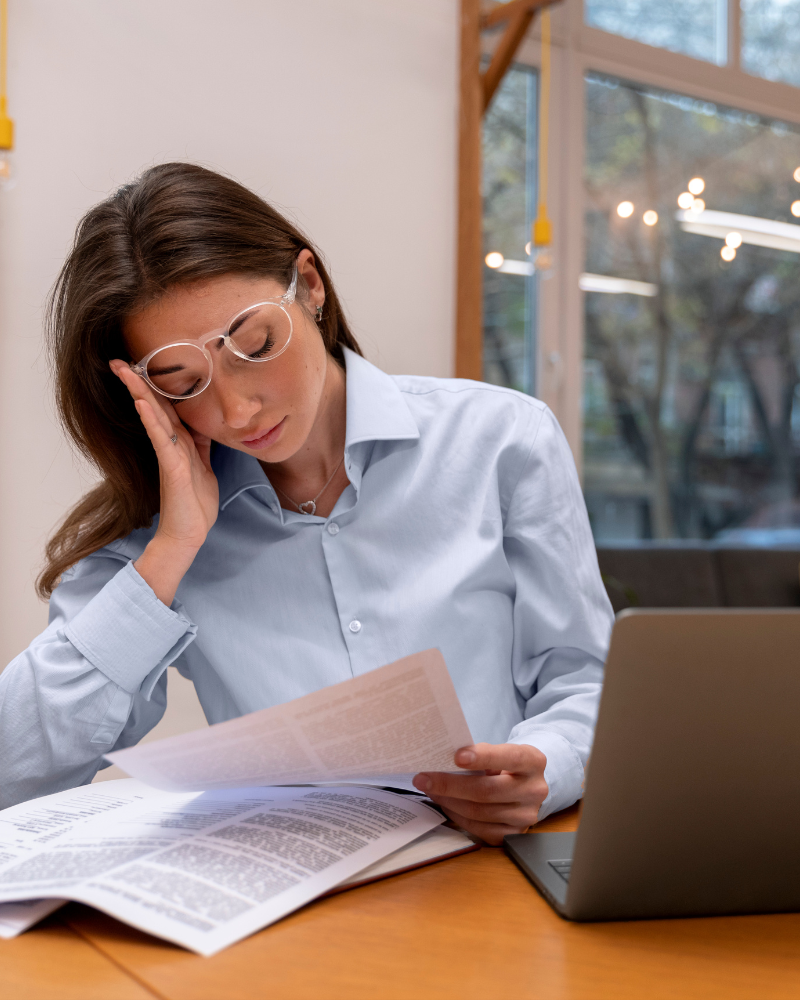 mujer joven con lentes revisa preocupada unos documentos