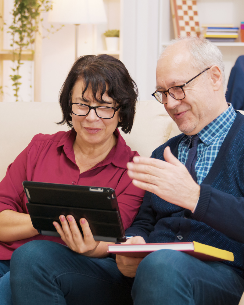 pareja adulta mayor revisa una tablet sonriendo