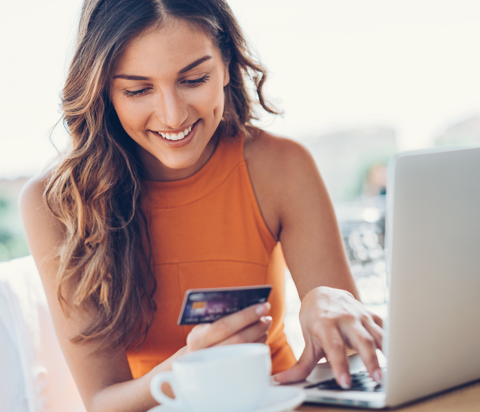 mujer navegando por Internet en un laptop mientras sujeta una tarjeta de crédito
